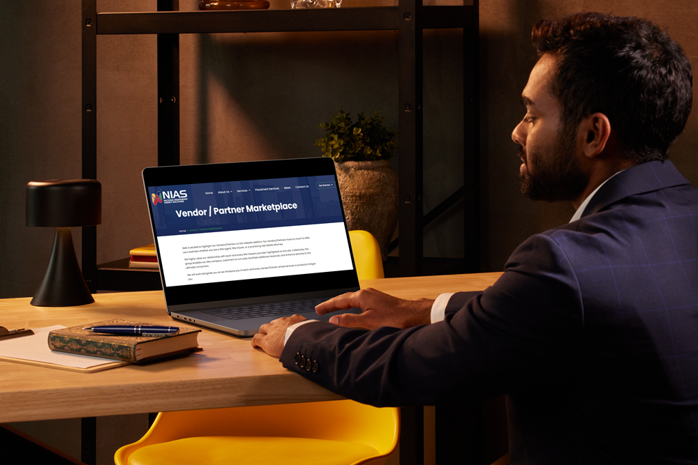 man in a blue suit sitting at table working on a laptop