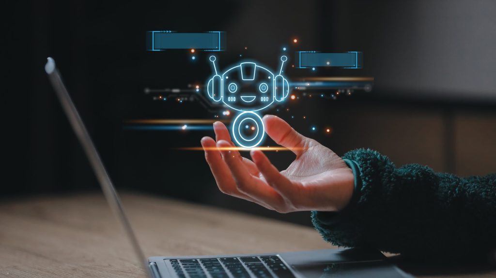 Person cupping a glowing, futuristic robot icon with holographic UI elements above a open laptop.